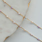 Delicate gold chain necklace with small beads on a light gray surface