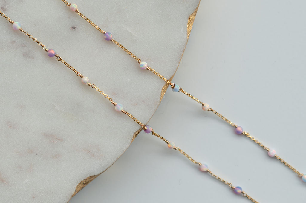 Delicate gold chain necklace with small beads on a light gray surface