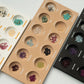 Three trays of gemstones arranged in a grid pattern on a light gray background