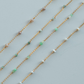 Gold chain necklaces with small beads on a light gray background