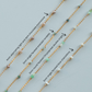 Gold fill chains with various gemstones on a light blue background