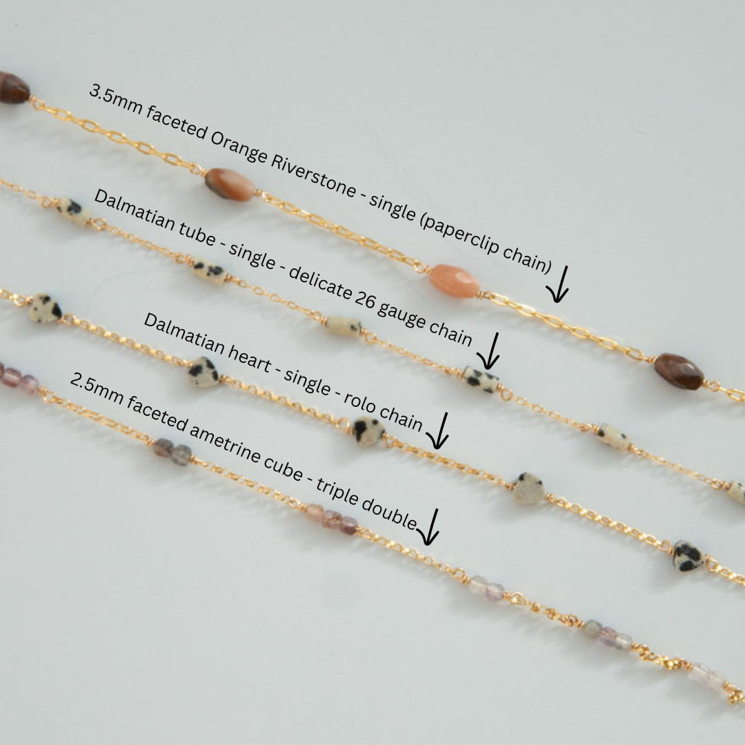 Four gold chains with different bead designs on a light gray background