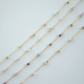 Gold necklaces with small beads on a light gray background