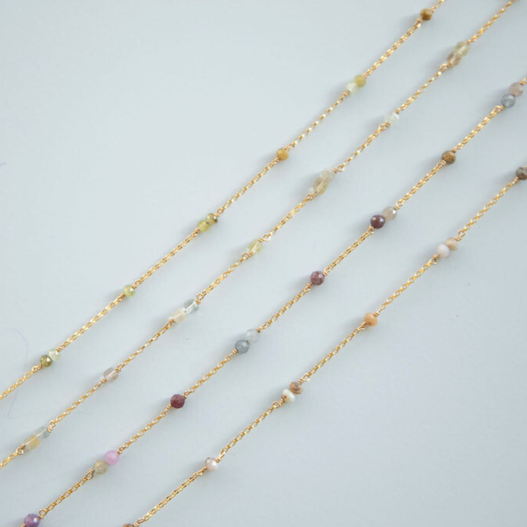 Gold necklaces with small beads on a light gray background