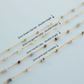 Gold chain with various gemstones on a light gray background