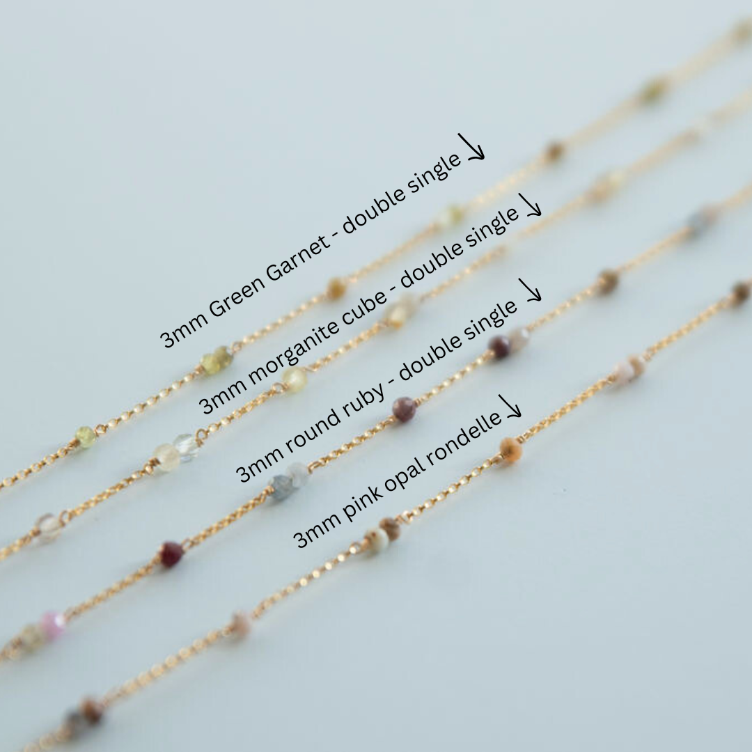 Gold chain with various gemstones on a light gray background