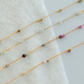 Gold fill chain with small beads on a white fabric background