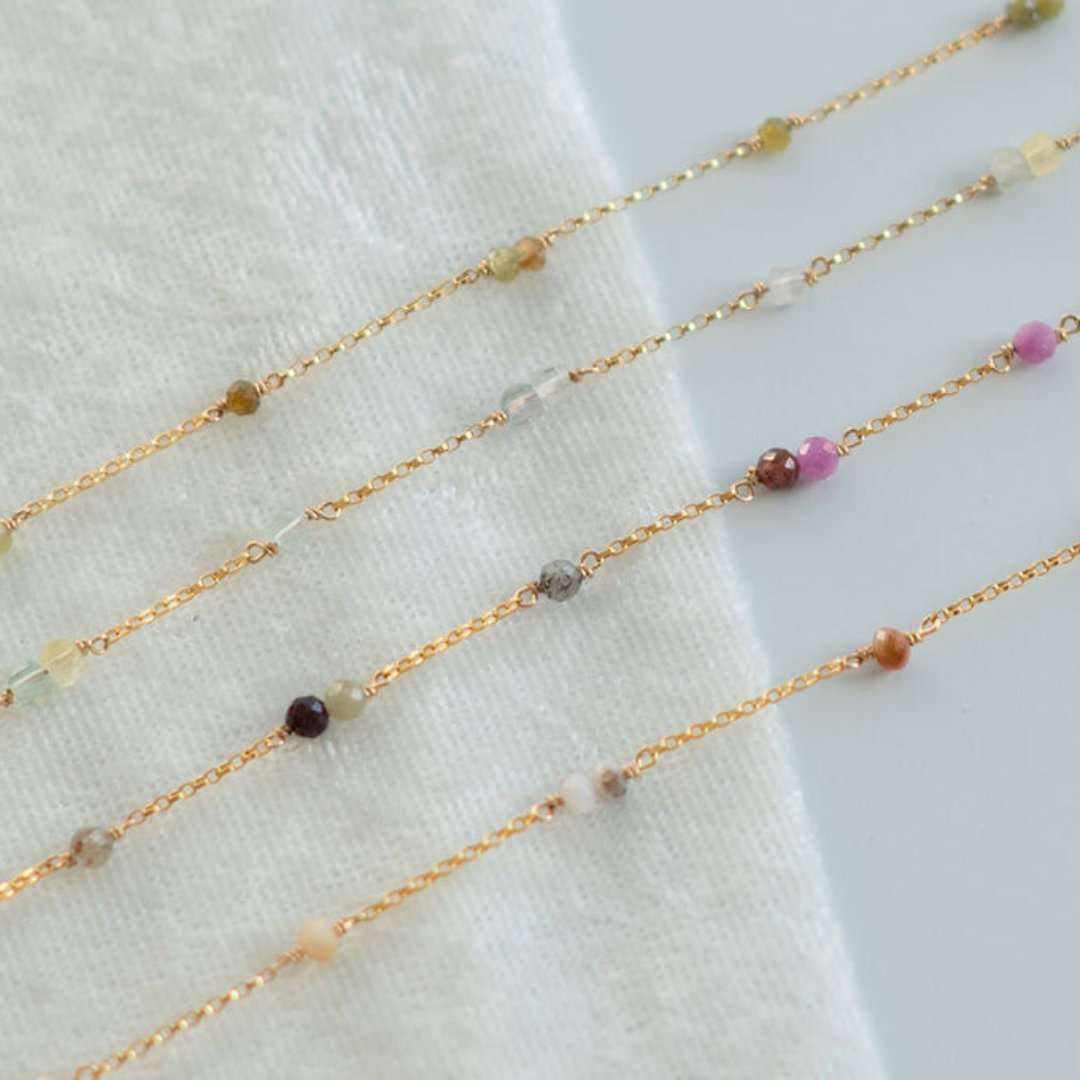 Gold fill chain with small beads on a white fabric background