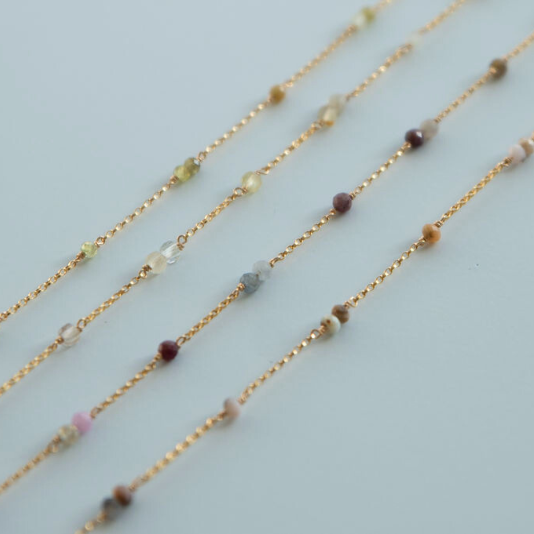 Three gold necklaces with small beads on a light blue background handmade