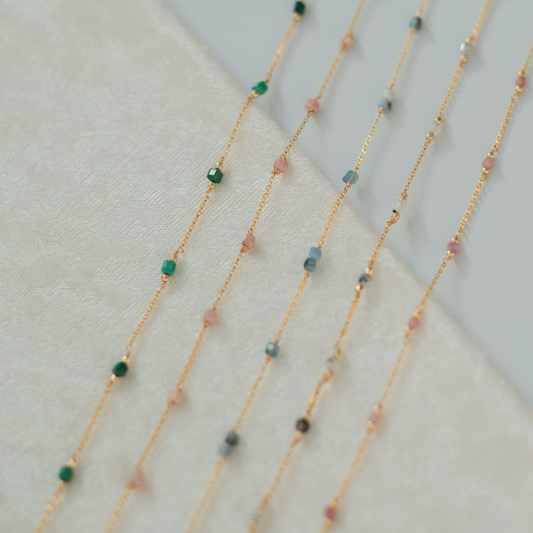 Gold necklaces with small beads on a light background