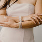 Woman wearing multiple pearl bracelets on her wrist with a neutral background