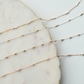 Three delicate gold fill necklaces on a marble surface