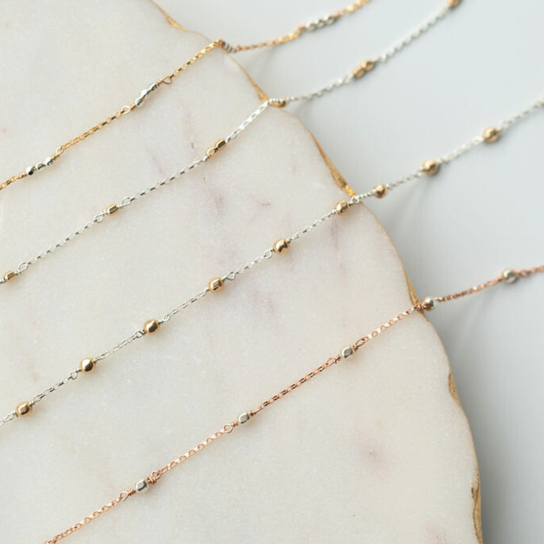 Three gold fill chain of different lengths on a marble surface