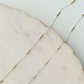 Close-up of a delicate gold and silver chain on a marble surface