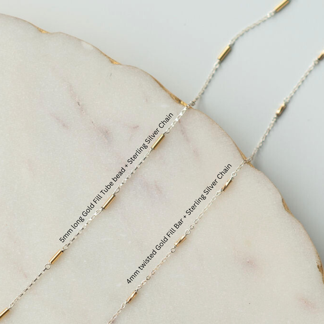 Close-up of gold fill and sterling silver chains on a marble surface