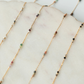 Gold necklaces with small beads on a marble surface