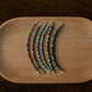 Set of silver and turquoise beaded bracelets on a wooden tray