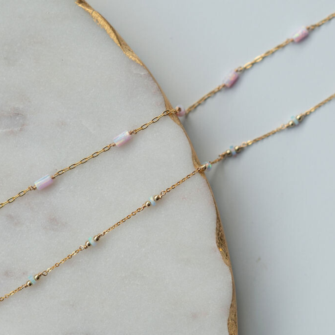 Gold chain necklace with small beads on a marble surface