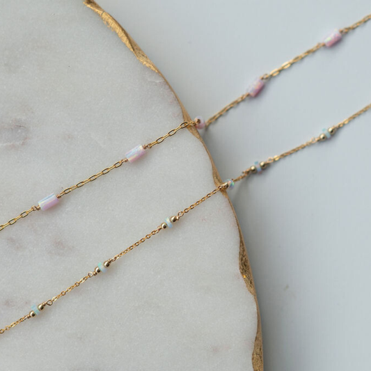 Gold chain necklace with small beads on a marble surface