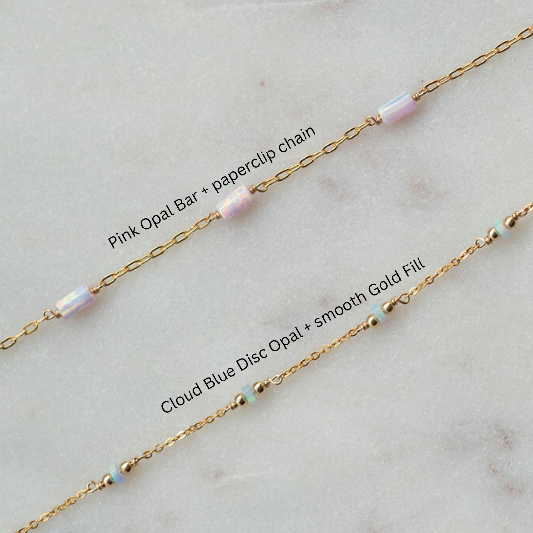 Gold chain with pink opal bar and cloud blue disc opal beads on a light gray background