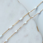 Gold chain necklace with opal on a marble surface