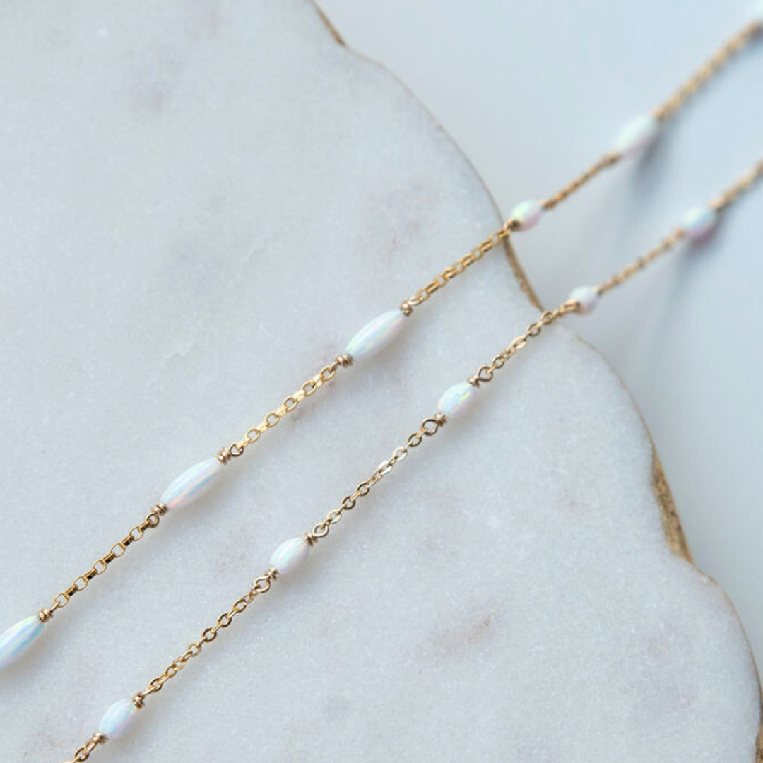 Gold chain necklace with opal on a marble surface