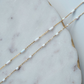 Gold fill chain necklace with opal beads on a marble surface