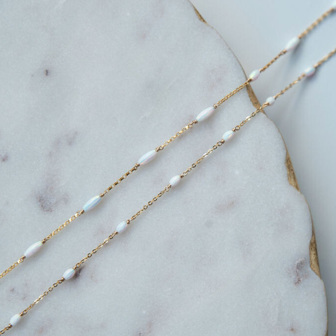 Gold fill chain necklace with opal beads on a marble surface