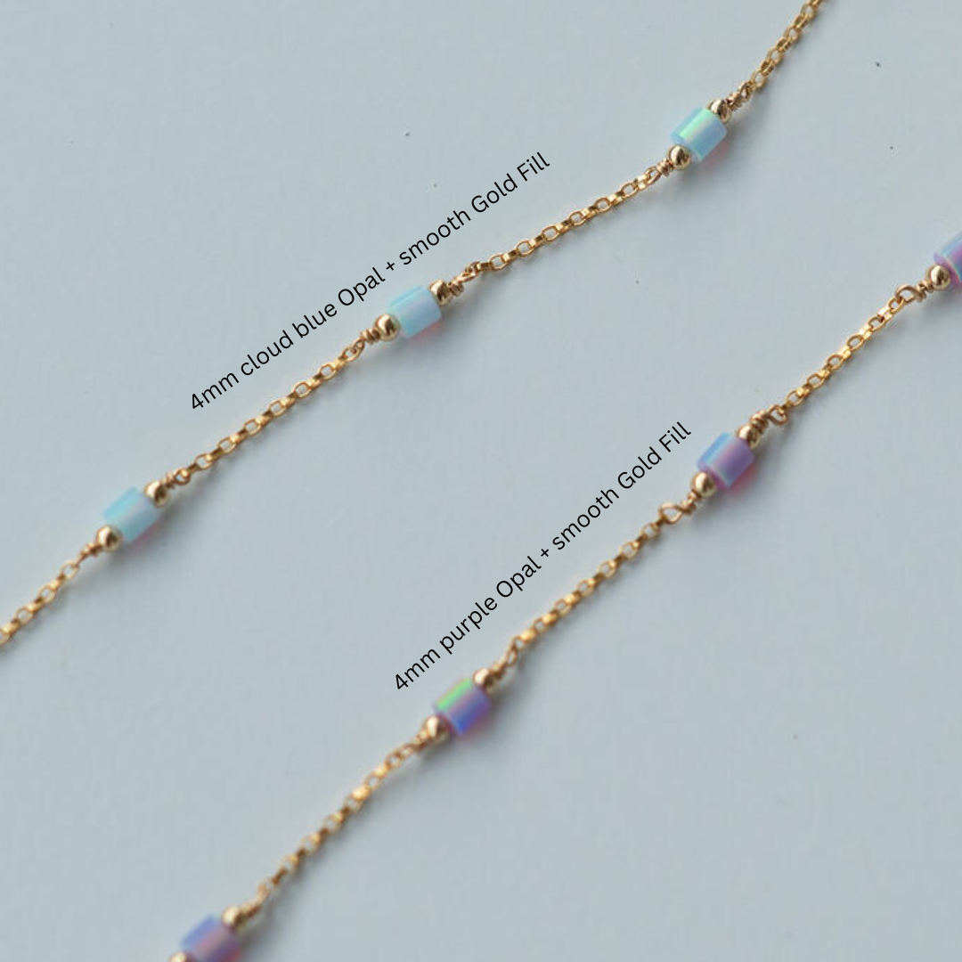 Gold chain necklace with cloud blue and purple opal beads on a light gray background
