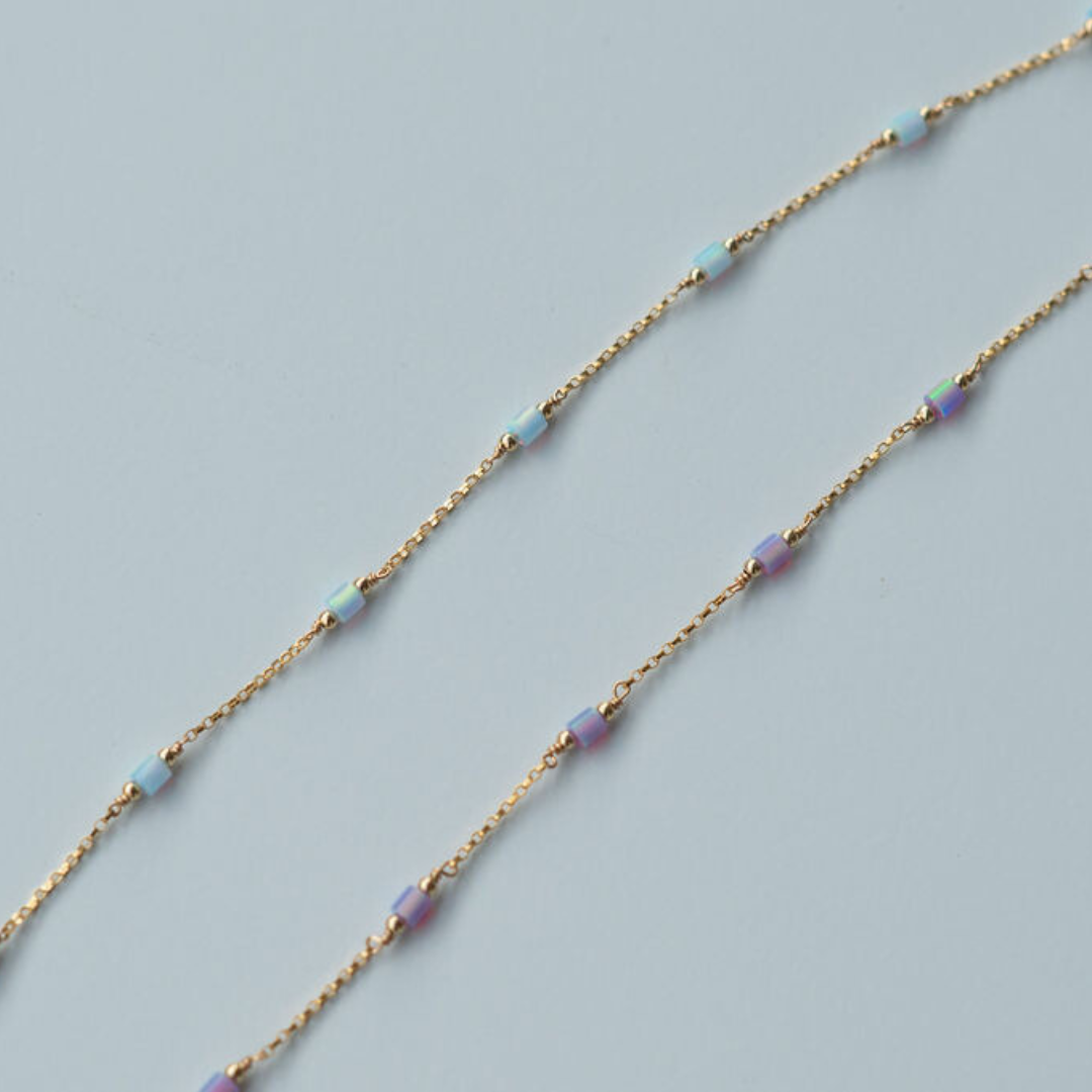 Gold  fill chain necklace with small beads on a light blue background