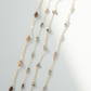 Layered necklace with beads on a light gray background