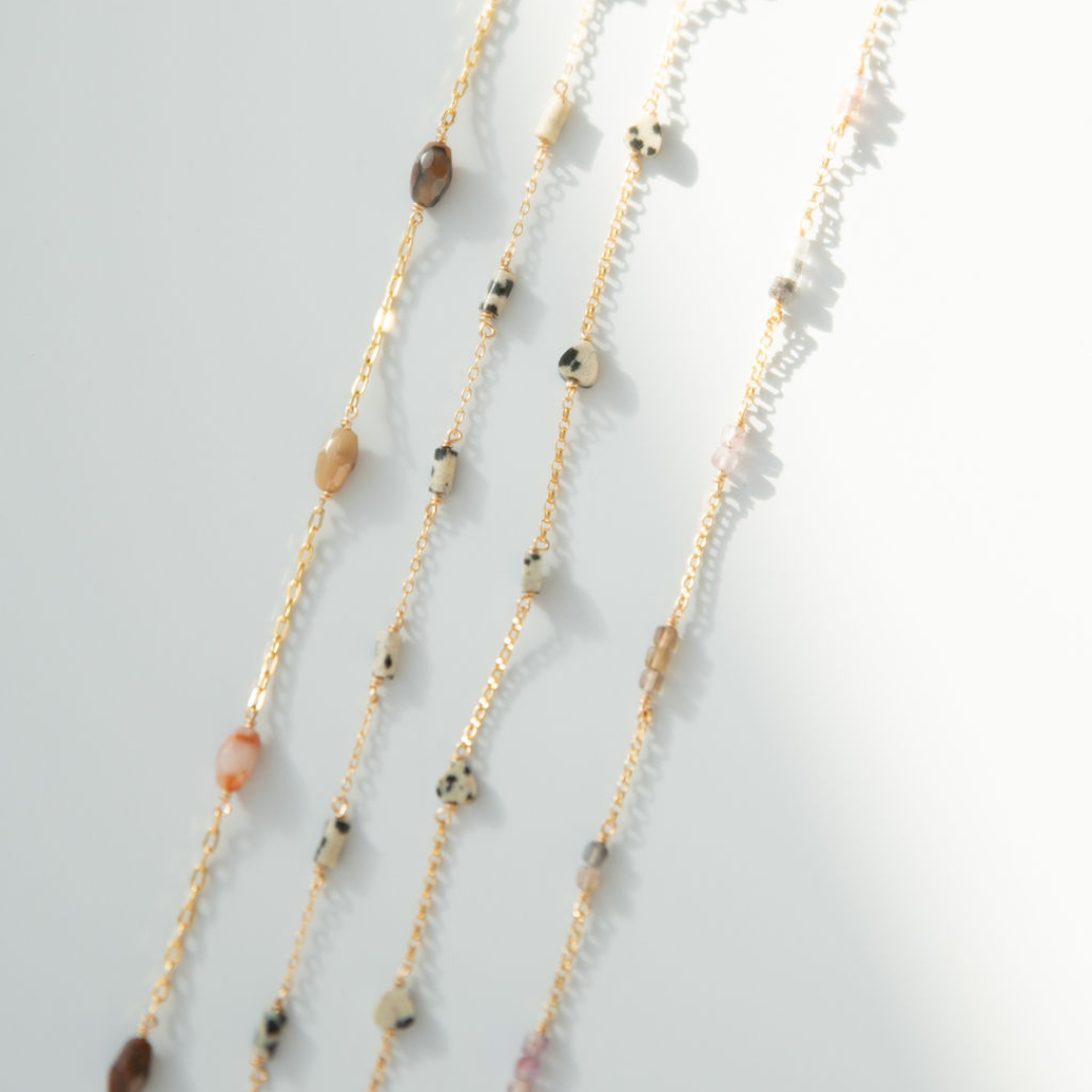 Layered necklace with beads on a light gray background