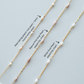 Three gold necklaces with pearl accents on a light gray background