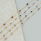 Gold fill chain necklaces with small beads on a textured surface