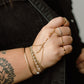 Hand with gold jewelry and tattoos wearing a black jacket
