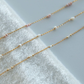 Gold chain necklaces with small beads on a white towel