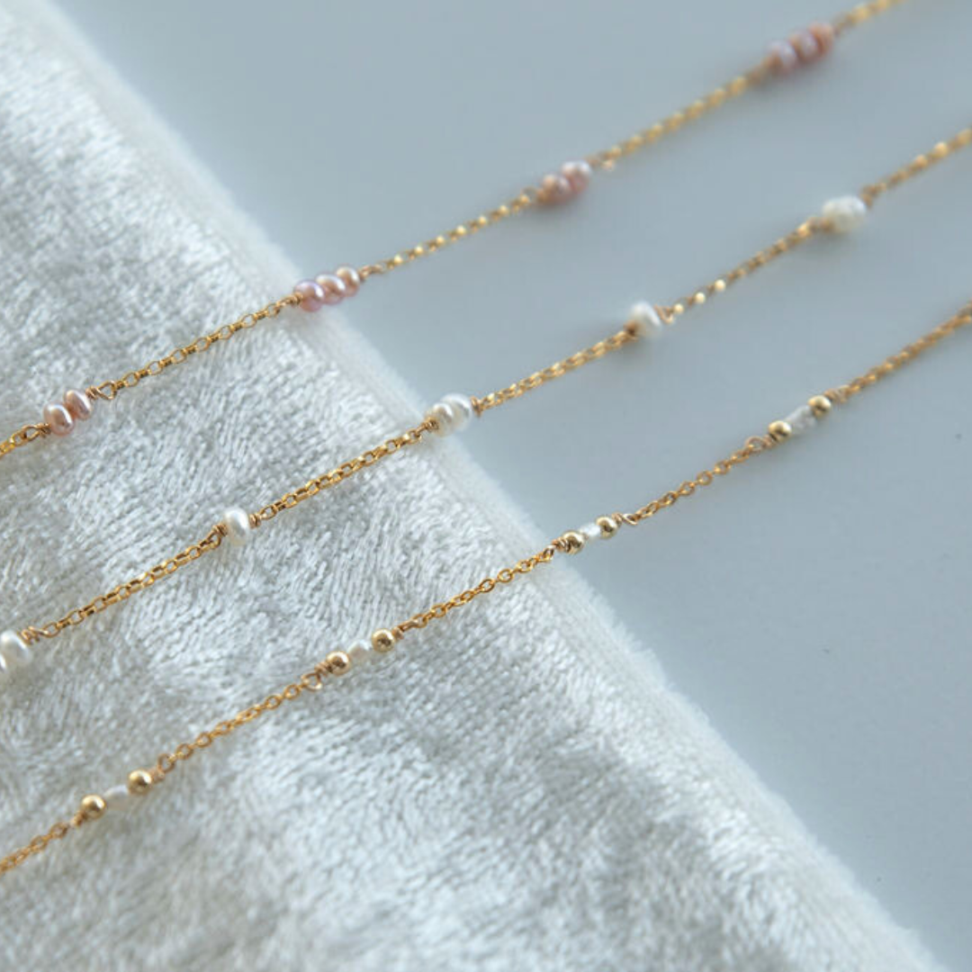 Gold chain necklaces with small beads on a white towel