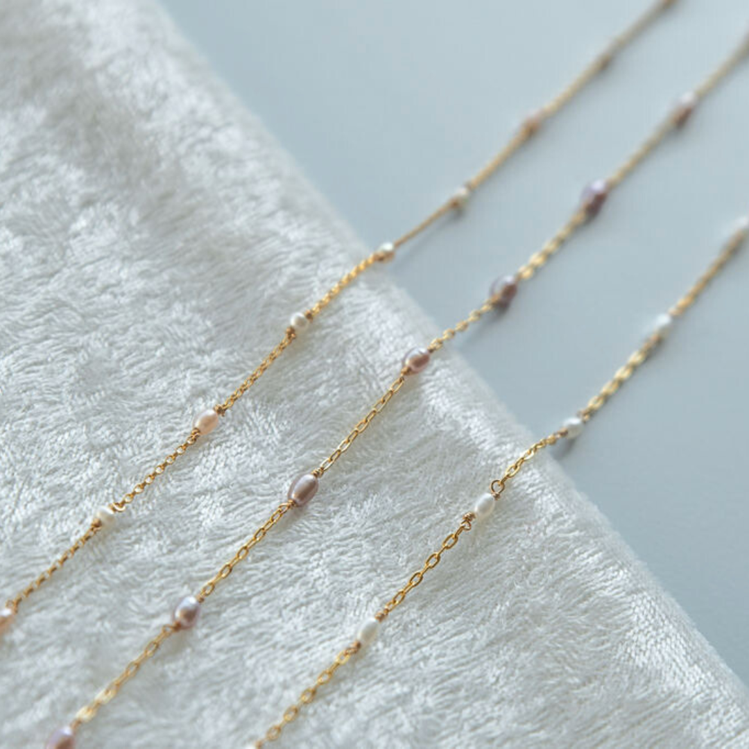 Gold chain necklace with small beads on a white towel
