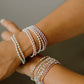 Close-up of a person's wrist wearing multiple pearl bracelets on a neutral background