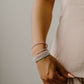 Person wearing multiple opal bracelets on a neutral background