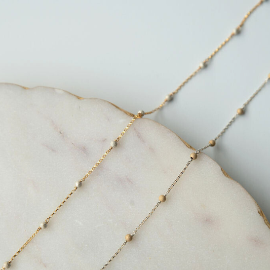 Delicate gold fill chain on a marble surface