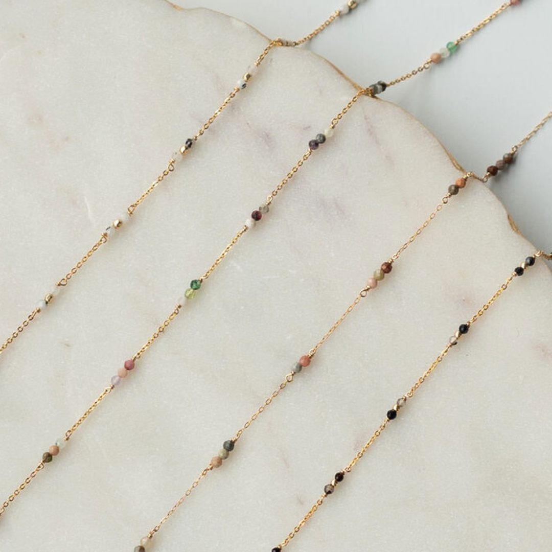 Gold chain necklace with small beads on a marble surface