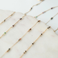 Gold chain necklace with small beads on a marble surface