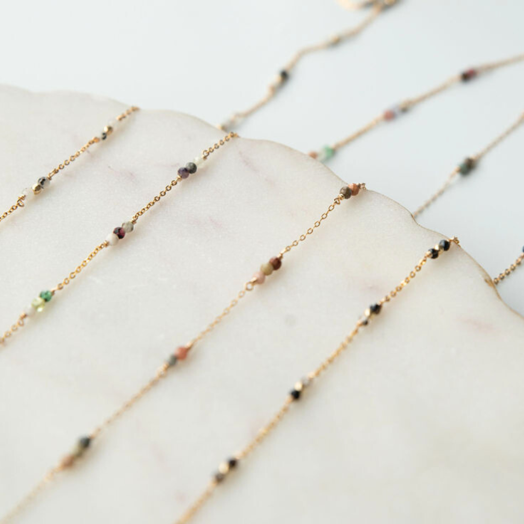 Gold chain necklace with small beads on a marble surface