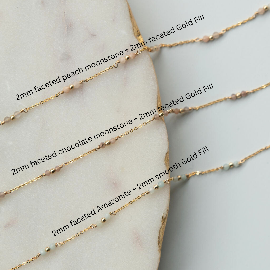 Three gold necklaces with gemstones on a marble surface