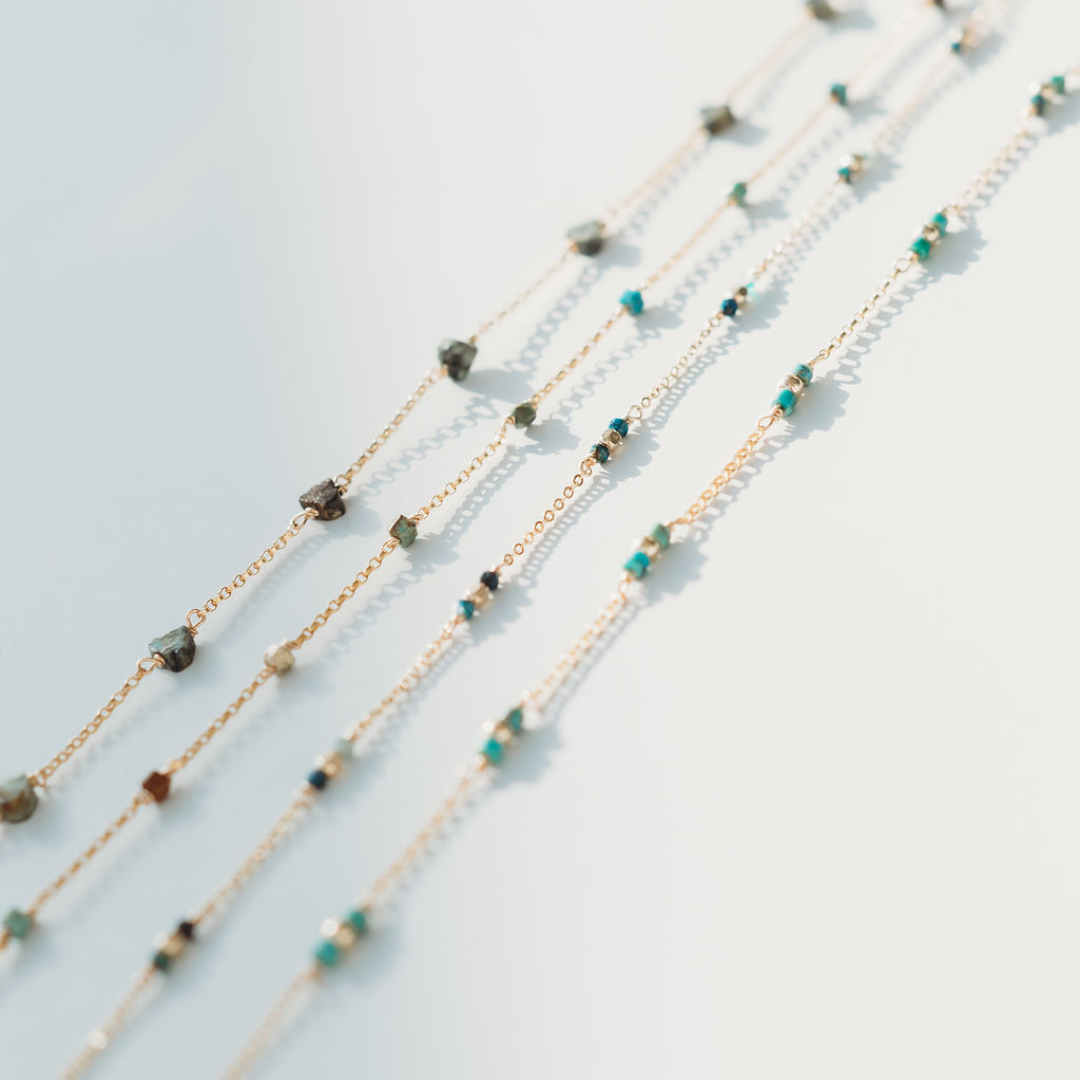 Multiple beaded necklaces on a light gray background
