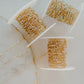 Three spools of gold gill handmade chain on a marble surface