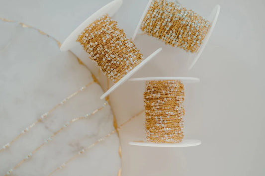 Three spools of gold gill handmade chain on a marble surface