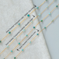 Turquoise beaded necklace with chain types labeled on a light gray background