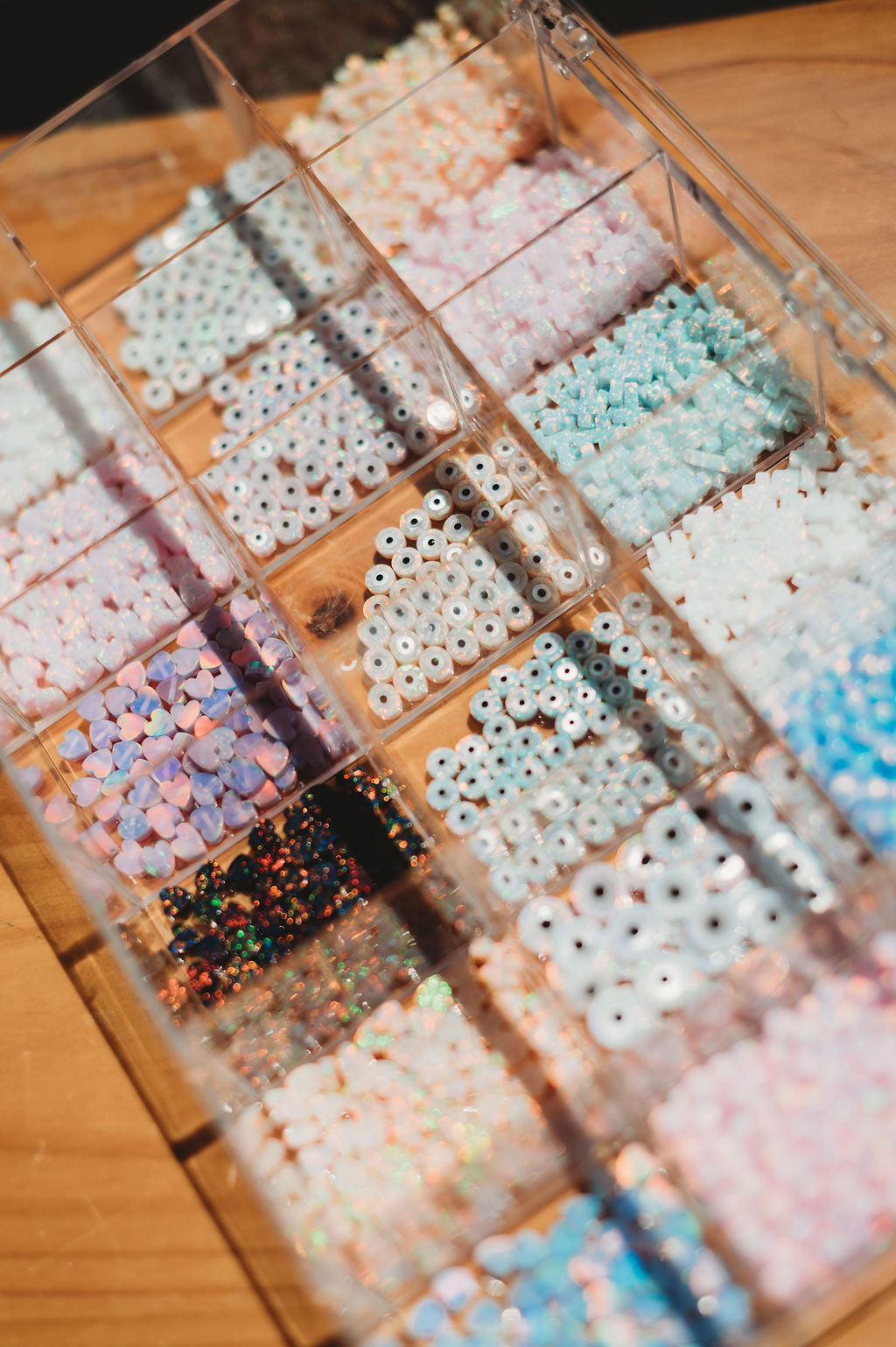 Assorted colorful beads in a clear container on a wooden surface